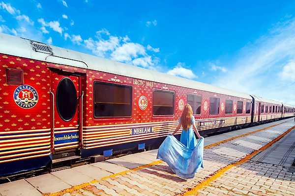 Maharajas Express luxury train at historic Indian railway station with elegant burgundy carriages